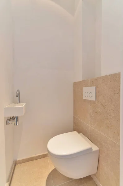 壁にベージュタイルのバスルームの隅にトイレがありその上に白い壁があります — ストック写真