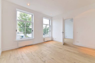 an empty room with wood flooring and large windows looking out onto the street in front of the apartment building