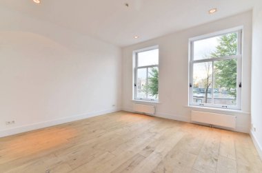 an empty room with wood flooring and large windows looking out onto the street in front of the apartment building