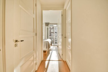 Beyaz kapılı ve yan yana ahşap döşemeli uzun bir koridor, oturma odasına açılıyor.