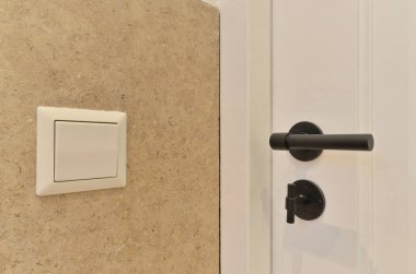 Siyah saplı beyaz bir kapı ve kapının kenarına bağlı olmayan bir elektrik prizi.