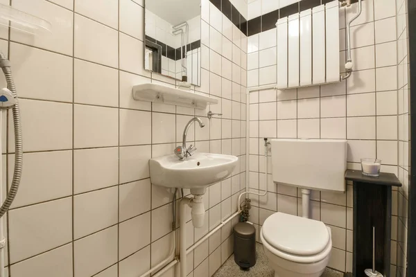Mała Łazienka Białymi Płytkami Czarnym Wykończeniem Wokół Toalety Zlewu Lustra — Zdjęcie stockowe