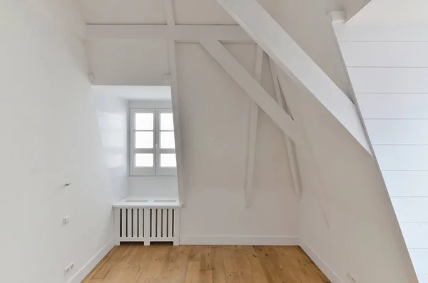 壁には木の床と白いペンキが描かれた空の部屋の隅に小さな窓があります — ストック写真