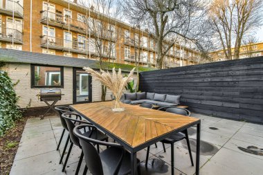 Sokakta kimsenin olmadığı apartmanın önünde masaları ve sandalyeleri olan bir avlu.