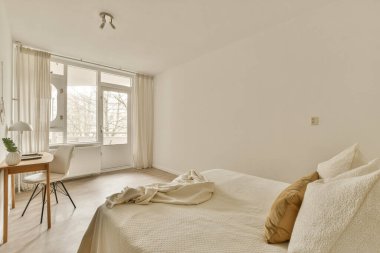 Yatağı, masası ve penceresi olan bir yatak odası. Dışarıdan sokağa bakıyor.