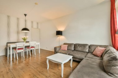 Kanepenin önündeki duvarda kanepe, masa ve televizyon olan bir oturma odası kırmızı perdeler.