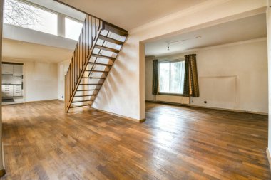 Ahşap döşemesi ve merdivenleri ikinci kata çıkan boş bir oturma odası sağ tarafta.