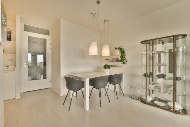 Mutfağa açılan ayna kapısının önünde iki sandalyesi ve masası olan bir yemek odası.