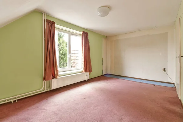 stock image an empty room with green walls and red carpeting on the floor there is a small window in the corner