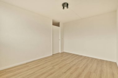 an empty room with white walls and wood flooring on the right side, there is a door in the corner