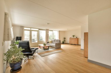 Odanın ortasında ahşap döşemeleri ve beyaz duvarları olan bir oturma odası balkona açılan açık bir kapıdır.