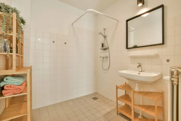 a bathroom with a sink, mirror and towel rack on the wall next to it is a white tiled floor