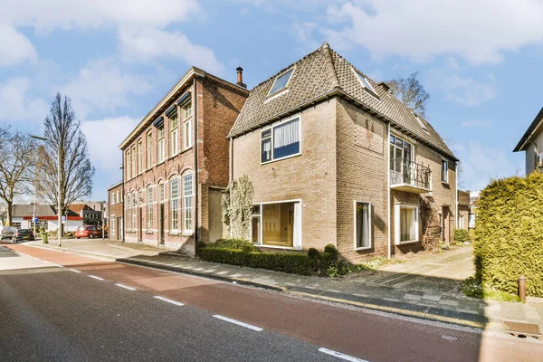 stock image an empty street with houses in the background and blue sky above, as seen from across the street there is a car parked on