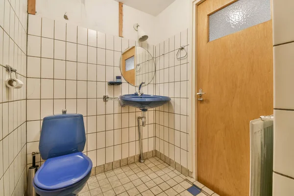 右側には青いトイレと白いタイル張りの壁が写り鏡がついています — ストック写真