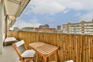 Sandalyeli bir balkon ve arka plandaki şehirli binalara bakan bir masa.