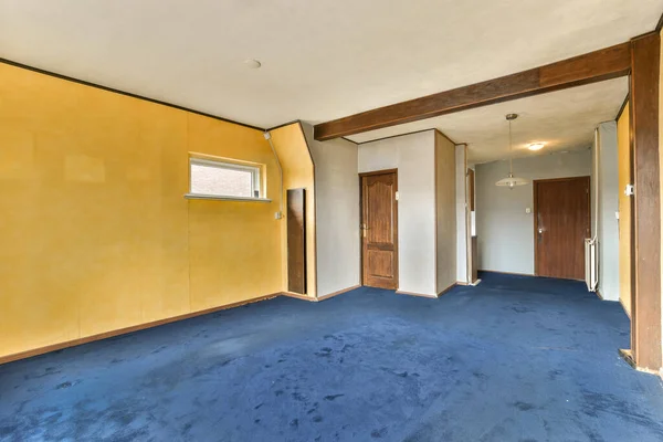 an empty room with yellow walls and blue carpeted floor, two doors open on either sides to the other side