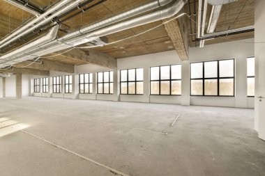 Boş bir ofis odası, açık tavan ve büyük pencereler çok temiz, kullanılmaya hazır.