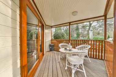 Arka plandaki ağaçlara bakan sandalyeli ve masalı bir veranda çok bulanık.