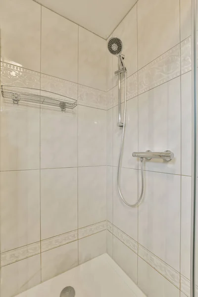 淋浴头和手放在连接在墙上的浴缸前面的浴室 — 图库照片