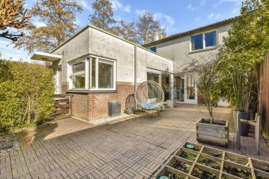 Arka bahçesinde tuğla kaldırımlar ve ağaçlarla çevrili açık deniz manzaralı bir bahçe.