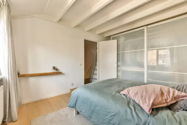 ベッドの上に白い壁と軽い木の床がある寝室には窓があります — ストック写真