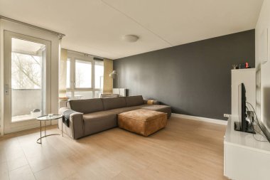 Kanepesi, televizyonu ve arka plandaki verandaya açılan büyük cam kapısı olan bir oturma odası.