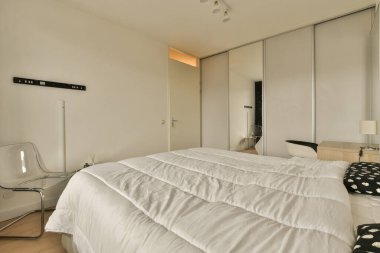 Yatağın önündeki duvarda yatak, sandalye ve ayna olan bir yatak odası siyah ve beyazdır.