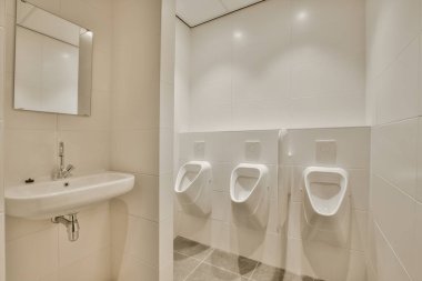 Duvarında iki urves olan bir banyo ve odanın diğer tarafında bir lavabo beyaz.