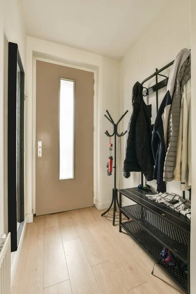 the inside of a house with clothes hanging on hooks and coat racks in front of door, next to entryway