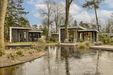 some houses that are in the water with trees and bushes around them on both side of the house there is a small pond clipart