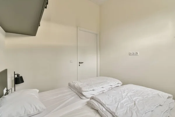 Łóżko Białymi Arkuszami Płaskim Ekranem Zamontowanym Nad Zagłówkiem Przed Łóżkiem — Zdjęcie stockowe