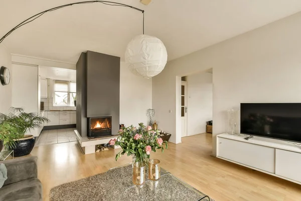 a living room with wood flooring and a large flat screen tv mounted on the wall in front of the fireplace