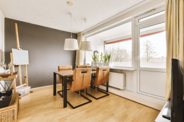 Ahşap döşemeli ve duvarlarında beyaz süslemeli bir yemek odası. Köşesinde bir televizyon var.