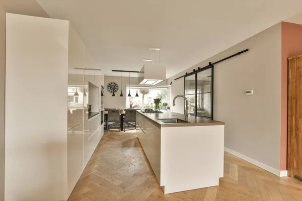 stock image a kitchen and dining area in a house with wood flooring, white walls and an open door leading to the living room