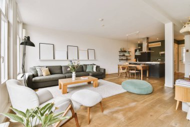 Odanın ortasında kanepeleri, sandalyeleri ve sehpası olan bir oturma odası geniş pencereli.