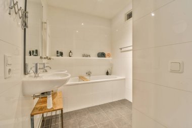 Lavabosu, aynası ve tuvalet kağıdı olan bir banyo. Odadaki küvetin yanındaki duvarda.