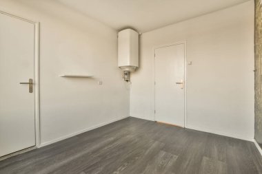 Her iki tarafında ahşap zemin ve beyaz kapılar olan boş bir oda. Odada kimse yok.