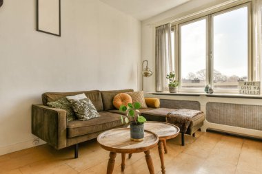 Oturma odası, bir kanepe, bir sehpa ve şehir manzarasına bakan büyük bir pencere.