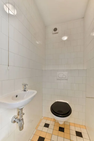 a bathroom with black and white tiles on the floor, sink and faucet in the shower stall area