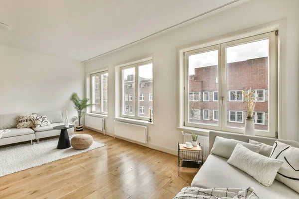 a living room with hardwood flooring and windows looking out onto the street in front of the apartments buildings