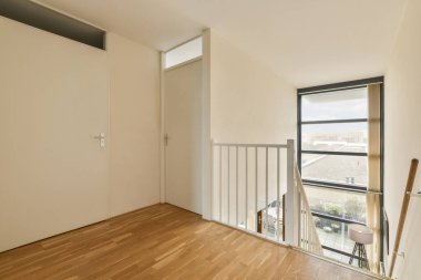 Ahşap zemin ve sürgülü cam kapılı boş bir oda balkon alanına açılıyor ve orada hiç mobilya yok.