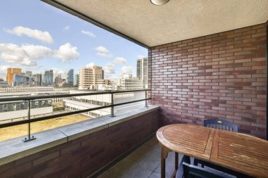 Kenar penceresinden şehri gören bir balkon ve verandada boş bir masa.