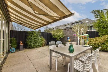 a patio area with a table and chairs under an awning over the outdoor dining set for two people to enjoy clipart