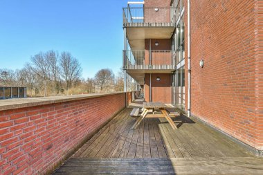 Ağaç döşemesi ve inşa edilmiş binanın yan tarafında kırmızı tuğla duvarlar olan bir dış alan.