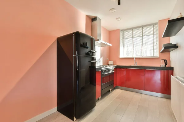 Uma Cozinha Com Paredes Vermelhas Aparelhos Pretos Nos Balcões Frente — Fotografia de Stock