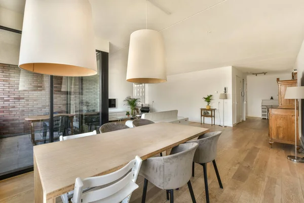 a kitchen and dining area in a house with wood floors, white walls, wooden flooring and large pendant lights
