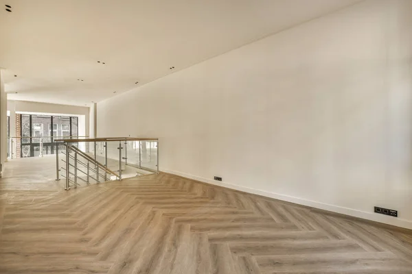 stock image an empty room with wood flooring and white walls in the background is a staircase leading up to a glass door