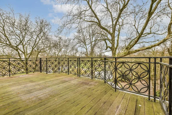 一个阳光明媚的春天 从上面取下的带有金属栏杆和树木的木制甲板 — 图库照片