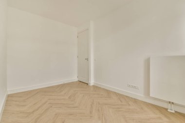 Beyaz duvarları ve ahşap döşemeleri olan boş bir oda. Köşesinde bir kapı var.