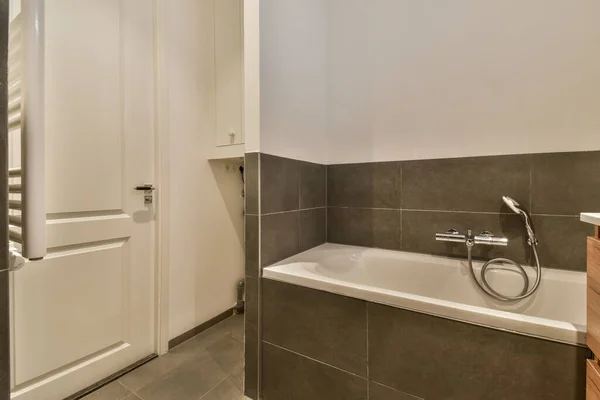 浴缸旁边墙上放有洗澡盆 镜子和厕纸的浴室 — 图库照片